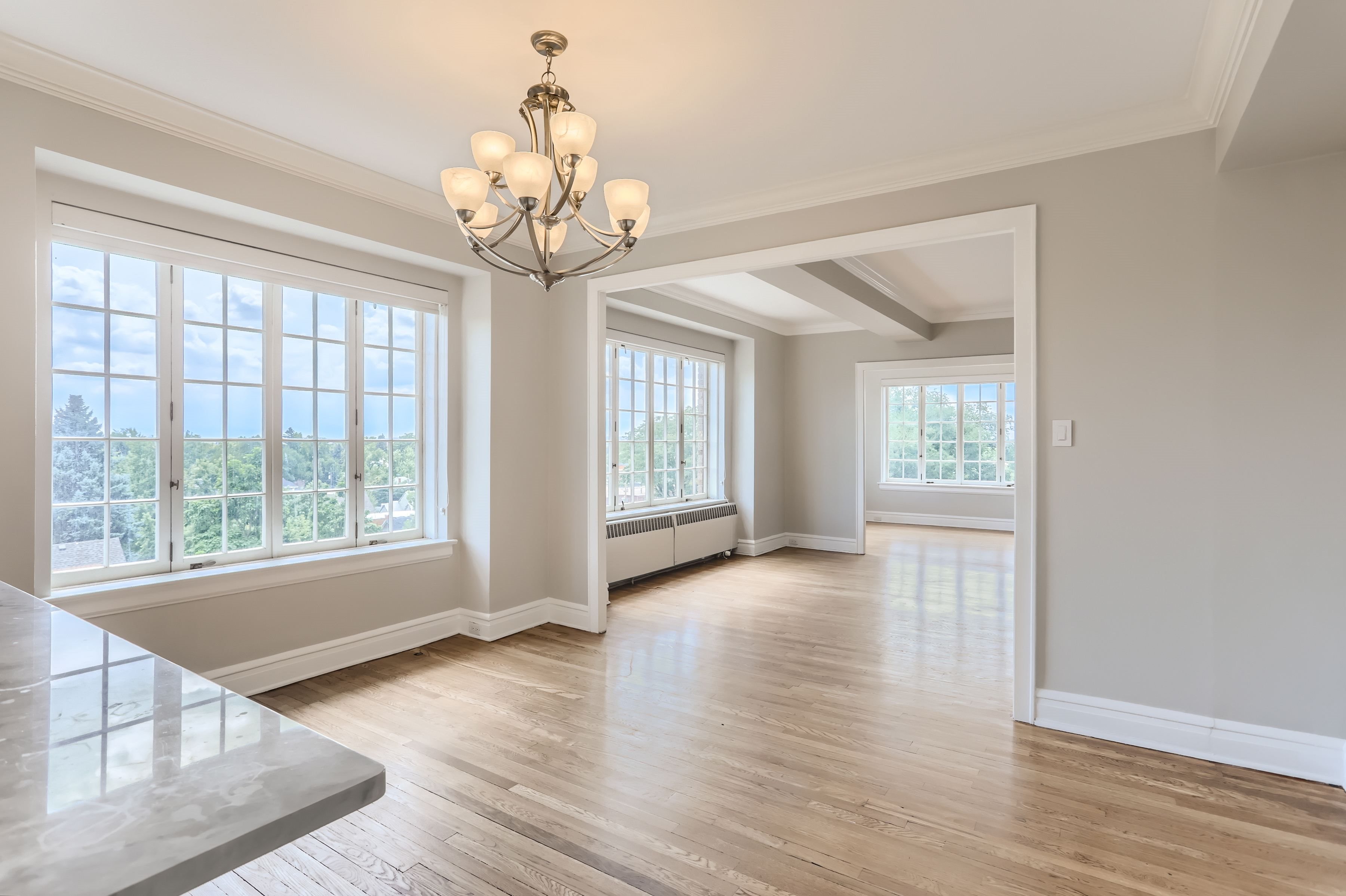 A well-lit room with a chandelier and large windows.